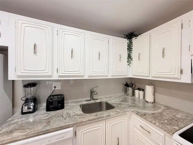 a kitchen with white cabinets and sink