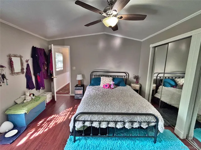 a bedroom with a bed and dresser with wooden floor