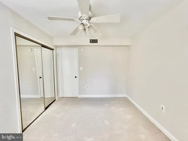 an empty room with a ceiling fan and a glass door