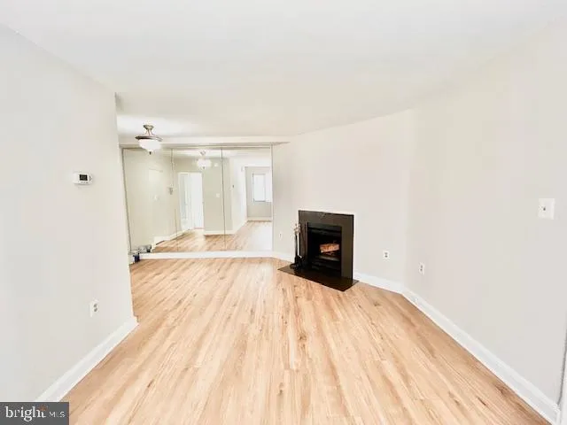 a view of empty room with wooden floor and fireplace