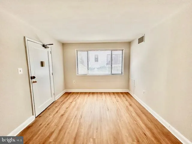 an empty room with wooden floor and windows