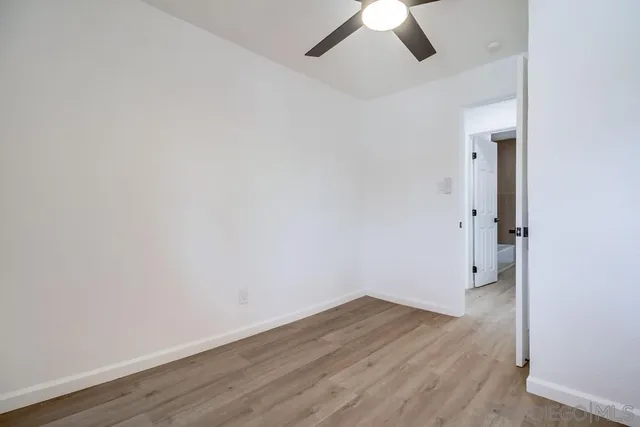 an empty room with wooden floor chandelier fan and windows