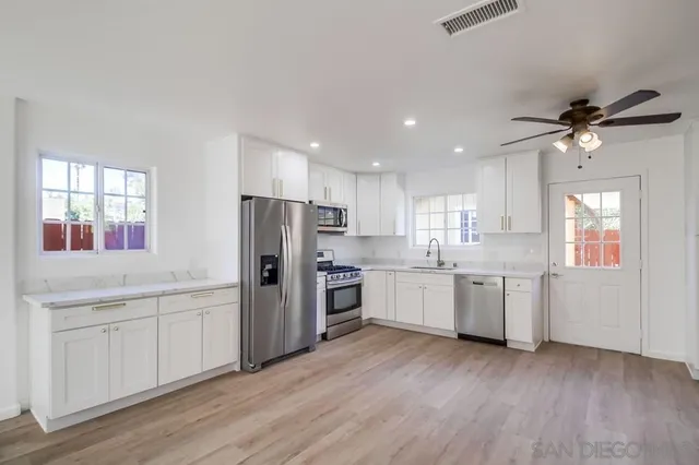 an empty room with wooden floor a ceiling fan and windows