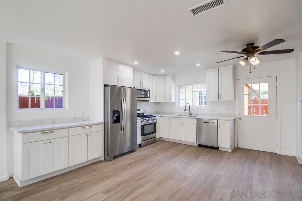 796 West Washington Avenue El Cajon, CA 92020 - Photo 38 of 71 a kitchen with granite countertop a refrigerator oven a sink dishwasher and white cabinets with wooden floor