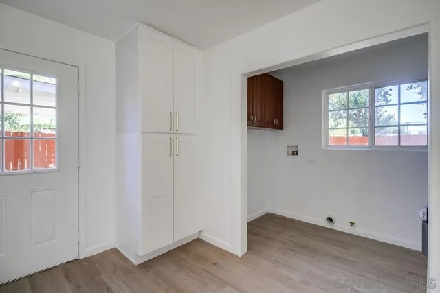 an empty room with wooden floor fan and windows