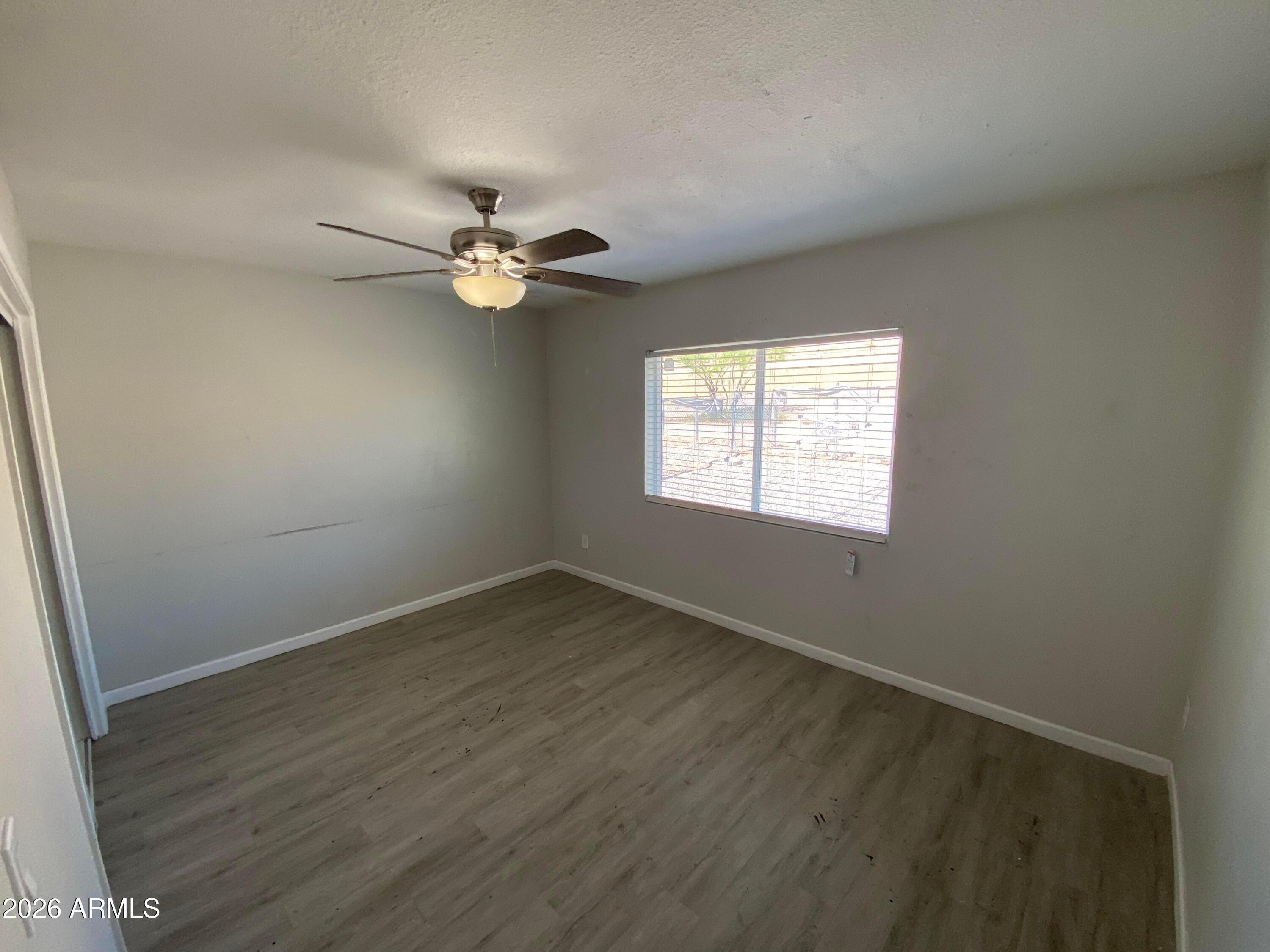 1124 North 27th Street, Unit 4 Phoenix, AZ 85008 - Photo 6 of 9 an empty room with wooden floor ceiling fan and window