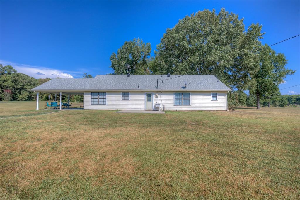 8835 Sebastian Road Keithville, LA 71047 - Photo 6 of 21 Expansive rear yard with mature trees, a covered patio, and white siding