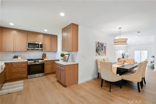 a kitchen with granite countertop kitchen island stainless steel appliances a stove a sink a refrigerator dining table and chairs