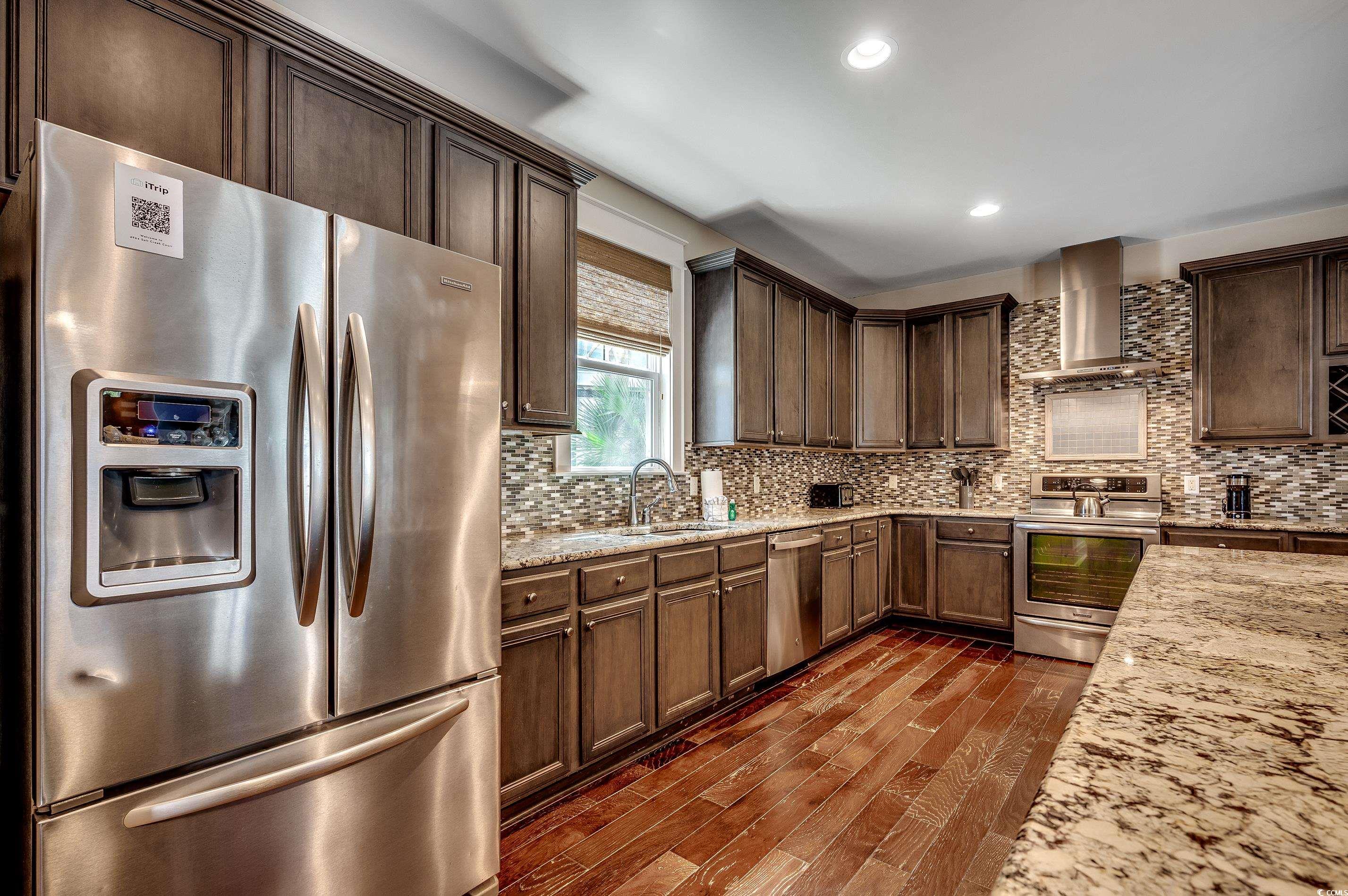 4964 Salt Creek Court North Myrtle Beach, SC 29582 - Photo 19 of 35 Kitchen with light stone counters, a sink, wall chimney exhaust hood, appliances with stainless steel finishes, and dark wood-style floors