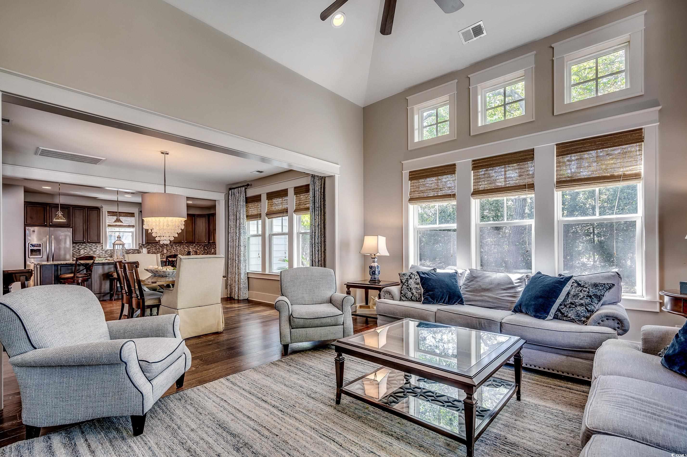 4964 Salt Creek Court North Myrtle Beach, SC 29582 - Photo 25 of 35 Living area featuring dark wood finished floors, a towering ceiling, visible vents, and ceiling fan with notable chandelier