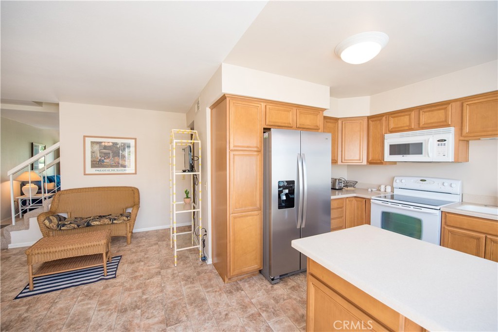 6087 Montecito Circle, Unit 4 Palm Springs, CA 92264 - Photo 14 of 45 a kitchen that has a refrigerator a stove and white cabinets