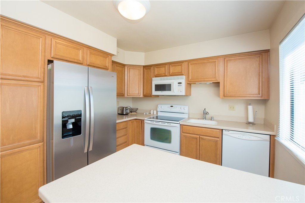 6087 Montecito Circle, Unit 4 Palm Springs, CA 92264 - Photo 15 of 45 a kitchen with a refrigerator a sink a stove a microwave and cabinets