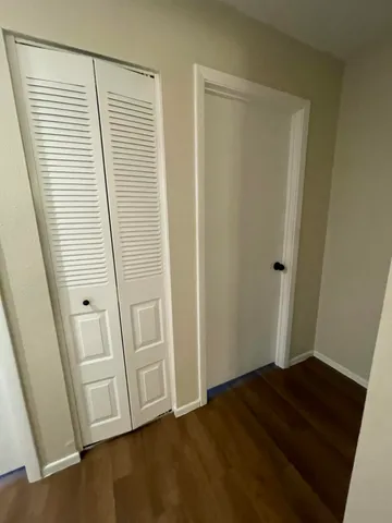 a view of a hallway with wooden floor and cabinet