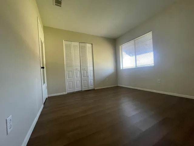 an empty room with wooden floor and windows with curtains