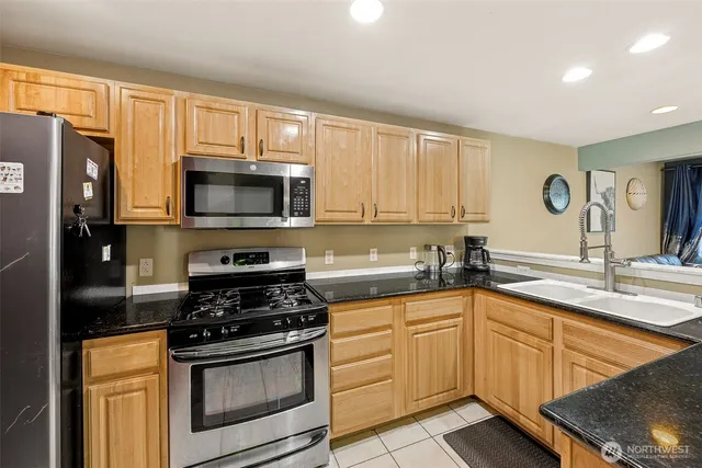 a kitchen with stainless steel appliances granite countertop a stove a sink and a microwave