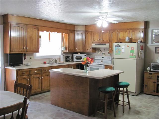 105 Adams Loop Tennessee Ridge, TN 37178 - Photo 7 of 20 a kitchen with kitchen island a stove a sink a refrigerator and chairs