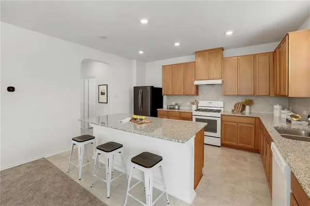 a kitchen with a sink a stove a refrigerator cabinets and a dining table