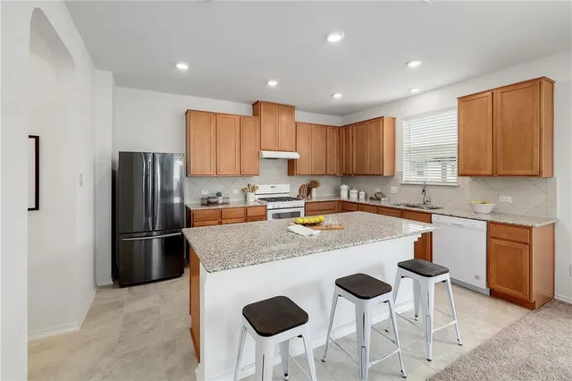 a kitchen with stainless steel appliances granite countertop a sink a stove a refrigerator and cabinets