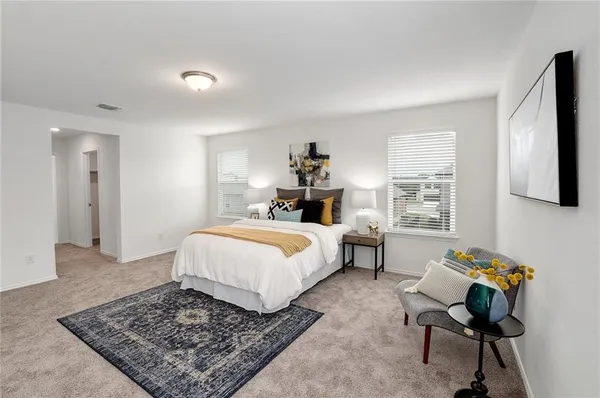 a spacious bedroom with a bed a rug and a window
