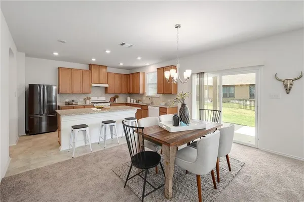 a kitchen with a dining table chairs and refrigerator