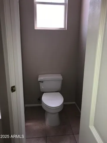 a white toilet sitting in a bathroom next to a window