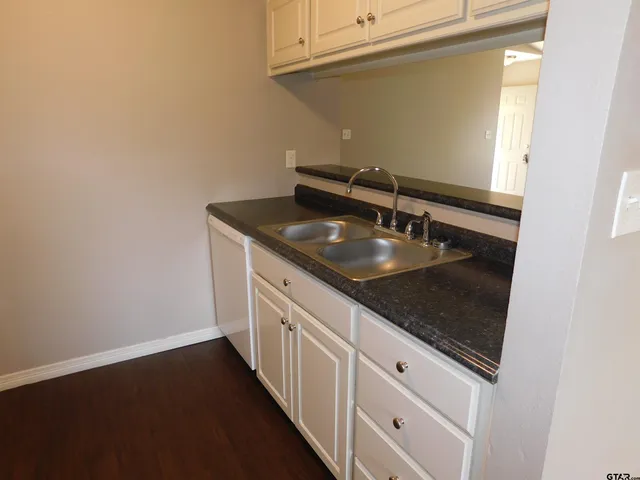 a kitchen with granite countertop white cabinets and a sink