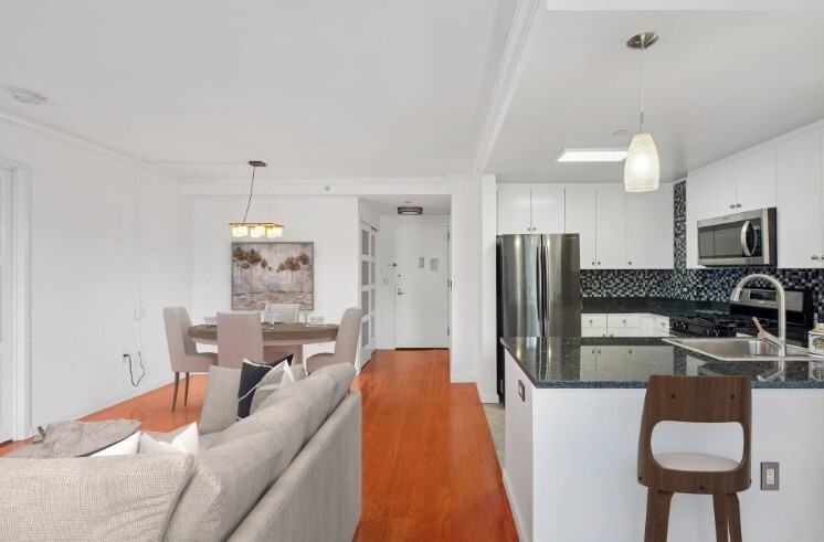 455 Main Street, Unit 4K Manhattan, NY 10044 - Photo 3 of 16 a kitchen with stainless steel appliances kitchen island granite countertop a refrigerator a stove a sink dishwasher and white cabinets with wooden floor