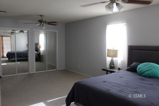 401 Ashton Street Ridgecrest, CA 93555 - Photo 23 of 36 a bedroom with a bed and a chandelier