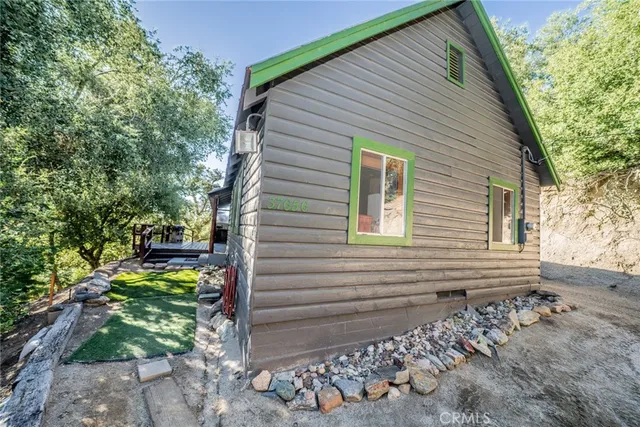 a view of a small house with yard and tree in the background
