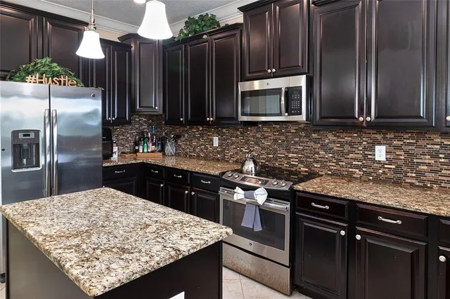 a kitchen with stainless steel appliances granite countertop wooden cabinets a stove a sink and a refrigerator