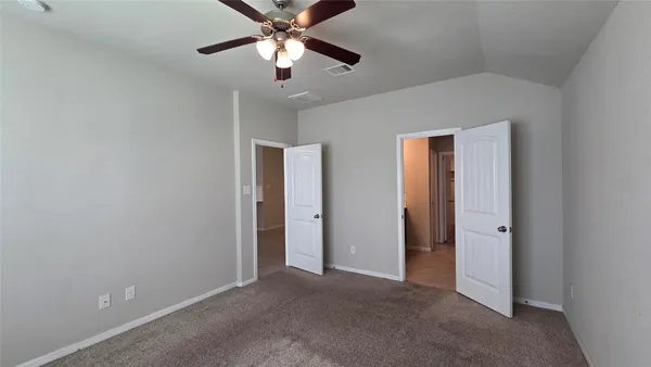 an empty room with closet and a chandelier fan