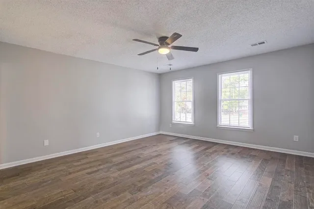 a view of an empty room with window and wooden floor