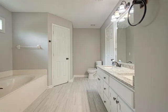 a spacious bathroom with a tub sink and mirror