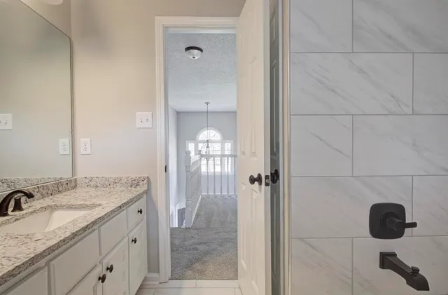 a bathroom with a granite countertop sink a mirror and shower