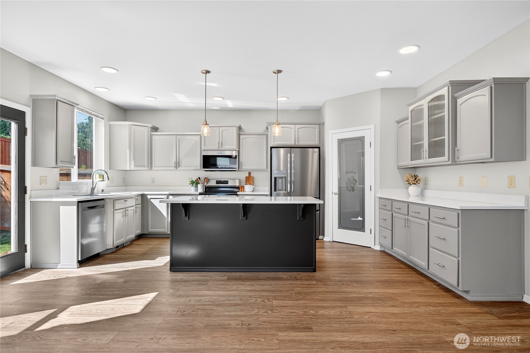 25621 160th Place Southeast Covington, WA 98042 - Photo 25 of 37 a kitchen with stainless steel appliances kitchen island granite countertop a stove a sink dishwasher a refrigerator and white cabinets with wooden floor