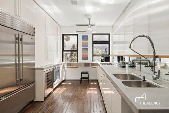 a large kitchen with a large window a sink and stainless steel appliances