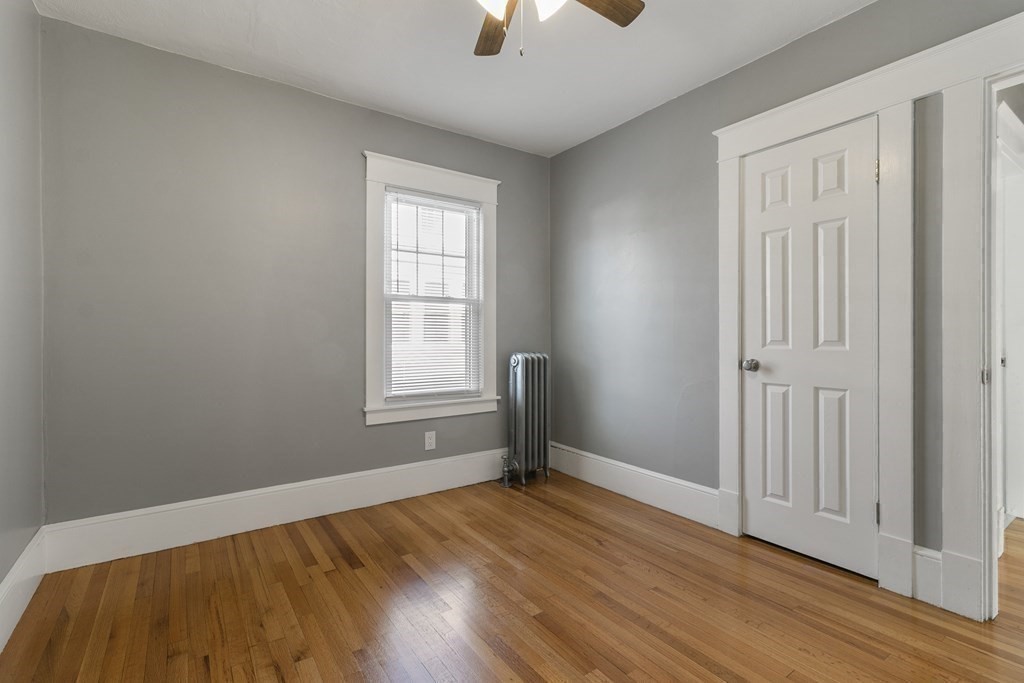 69 Redlands Street Springfield, MA 01104 - Photo 12 of 29 an empty room with wooden floor chandelier fan and windows