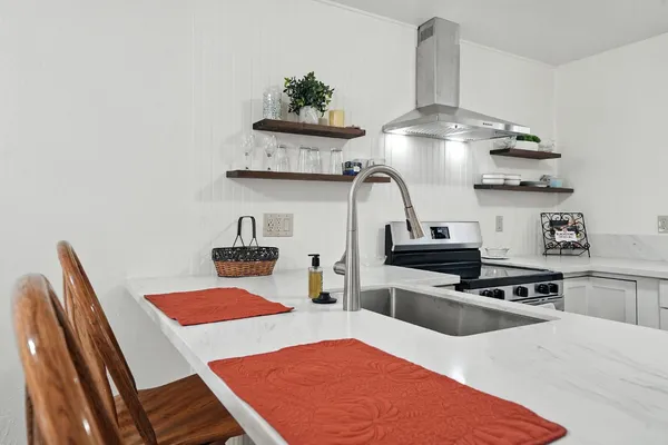 a kitchen with stainless steel appliances granite countertop a sink a stove and a wooden floors