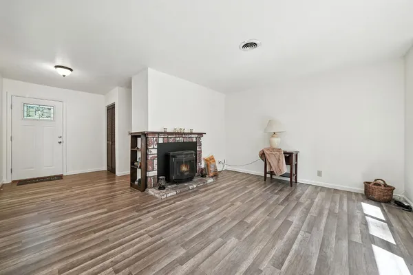 a view of empty room with wooden floor and fireplace