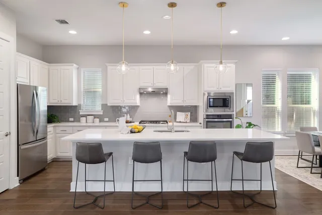 a kitchen with stainless steel appliances kitchen island granite countertop a refrigerator and microwave