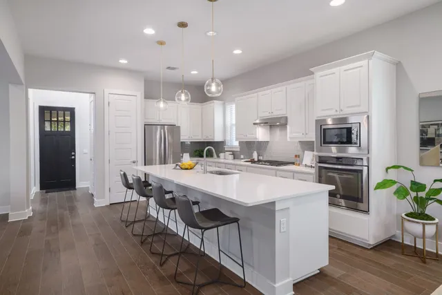 a kitchen with stainless steel appliances a dining table chairs stove refrigerator and microwave