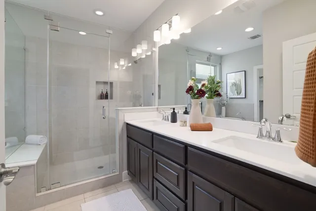 a bathroom with a double vanity sink mirror and shower