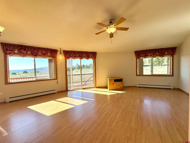 a view of an empty room with a window and wooden floor
