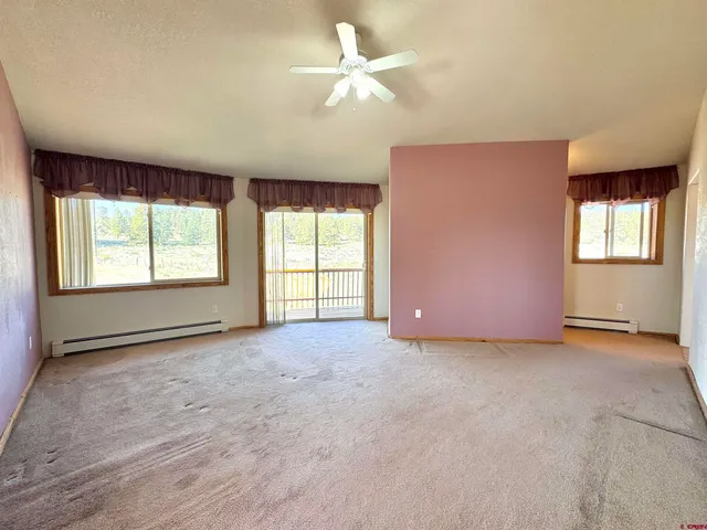 an empty room with chandelier fan and windows