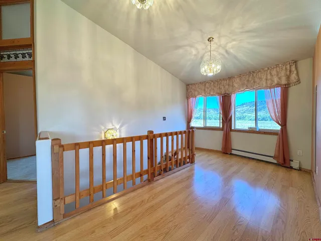 a view of an empty room with wooden floor and fan