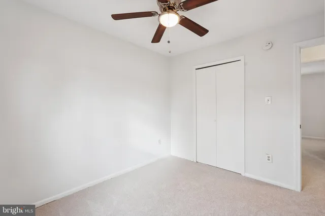 an empty room with a fan & a ceiling fan