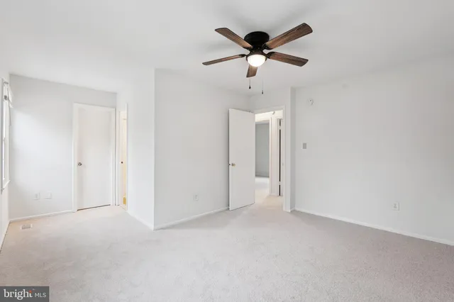 an empty room with a ceiling fan and window