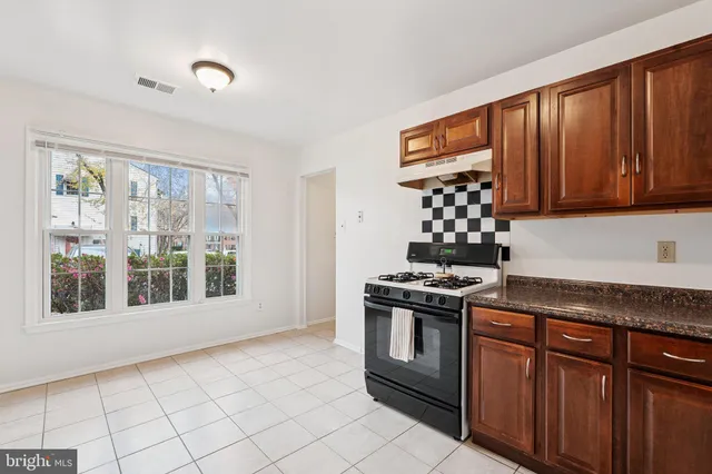 a kitchen with granite countertop a stove top oven cabinetry a sink and a window