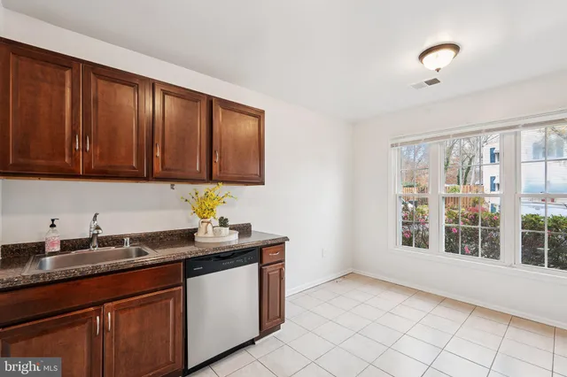 a kitchen with granite countertop a sink cabinets stainless steel appliances and a window