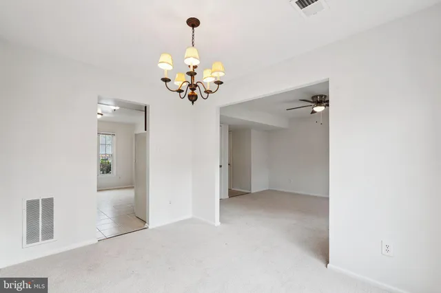a view of an empty room and chandelier fan